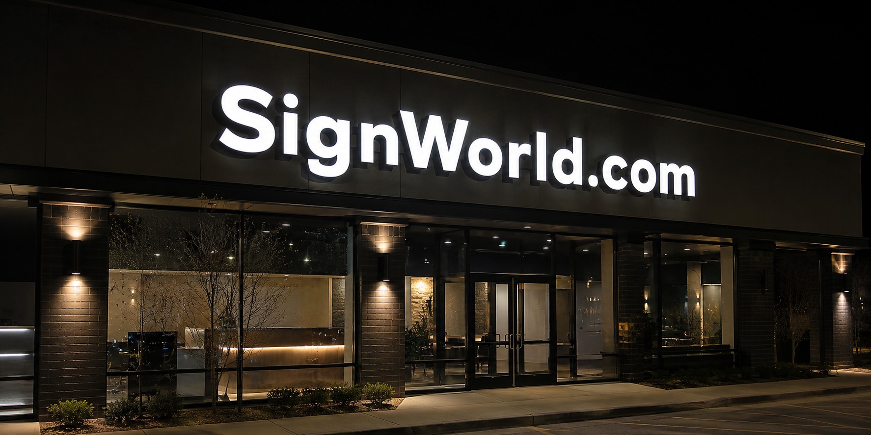 Illuminated SignWorld.com channel letters on a storefront at night